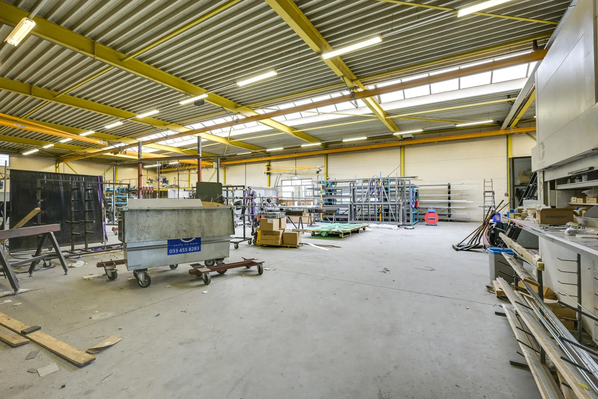 Ruime, industriële werkplaats aan de Tennesseedreef met stellingen, machines en materialen.