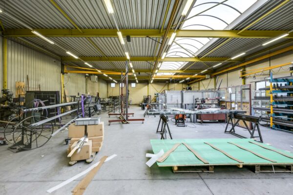 Interieur van een ruime en goed verlichte werkplaats aan de Tennesseedreef met metaalbewerkingsmachines en werkmaterialen.