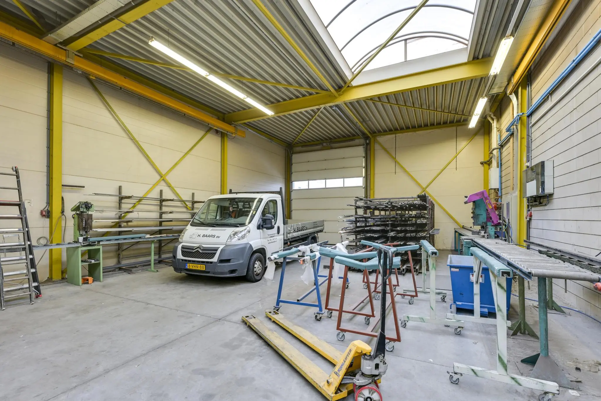 Industriële werkplaats aan de Tennesseedreef met een bedrijfswagen, metaalbewerkingsmachines en opslagrekken.