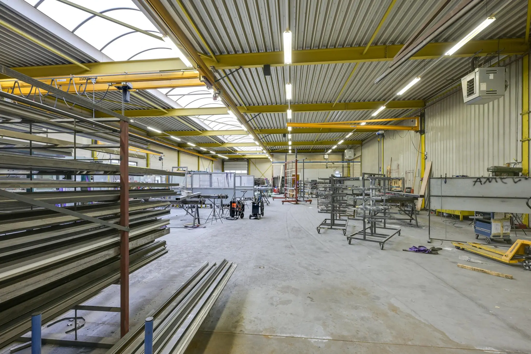 Ruime industriële werkplaats aan de Tennesseedreef met metalen rekken, werkbanken en zware machines.