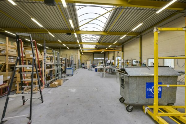 Ruime industriële werkplaats aan de Tennesseedreef met rekken, gereedschappen en een afvalcontainer.