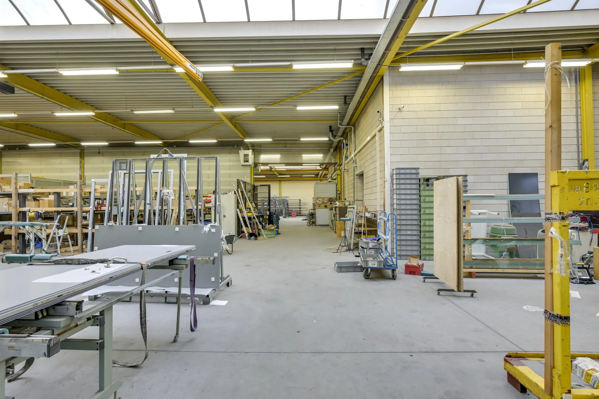 Ruime en goed verlichte werkplaats aan de Tennesseedreef met metalen rekken, bouwmaterialen en gereedschappen.