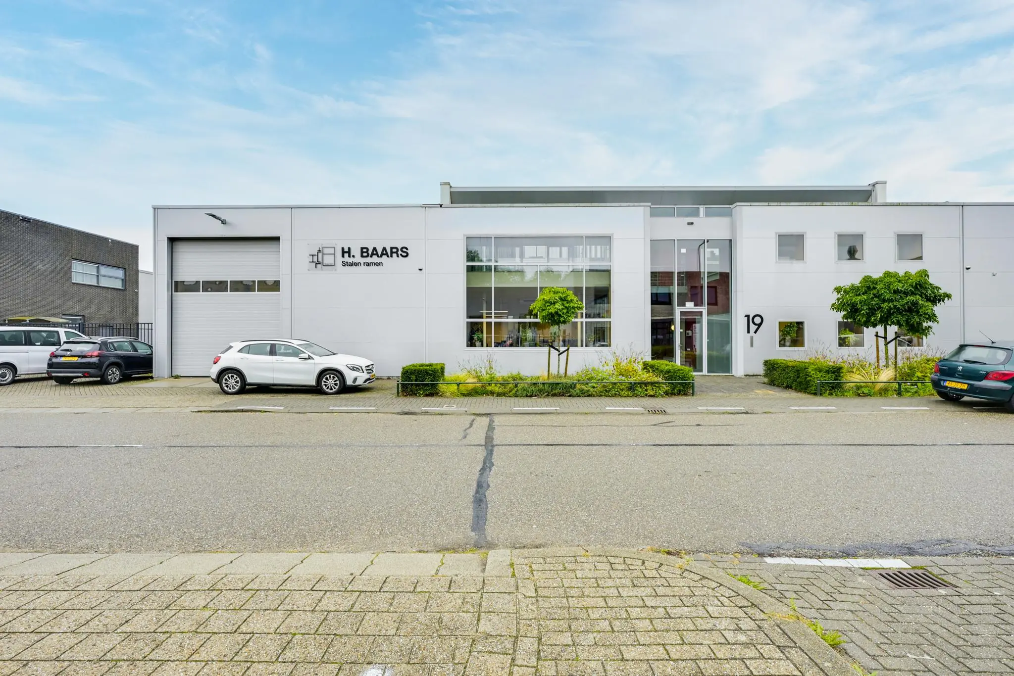 Voorgevel van een modern bedrijfsgebouw aan de Tennesseedreef met het logo van H. Baars Stalen Ramen en geparkeerde auto's.