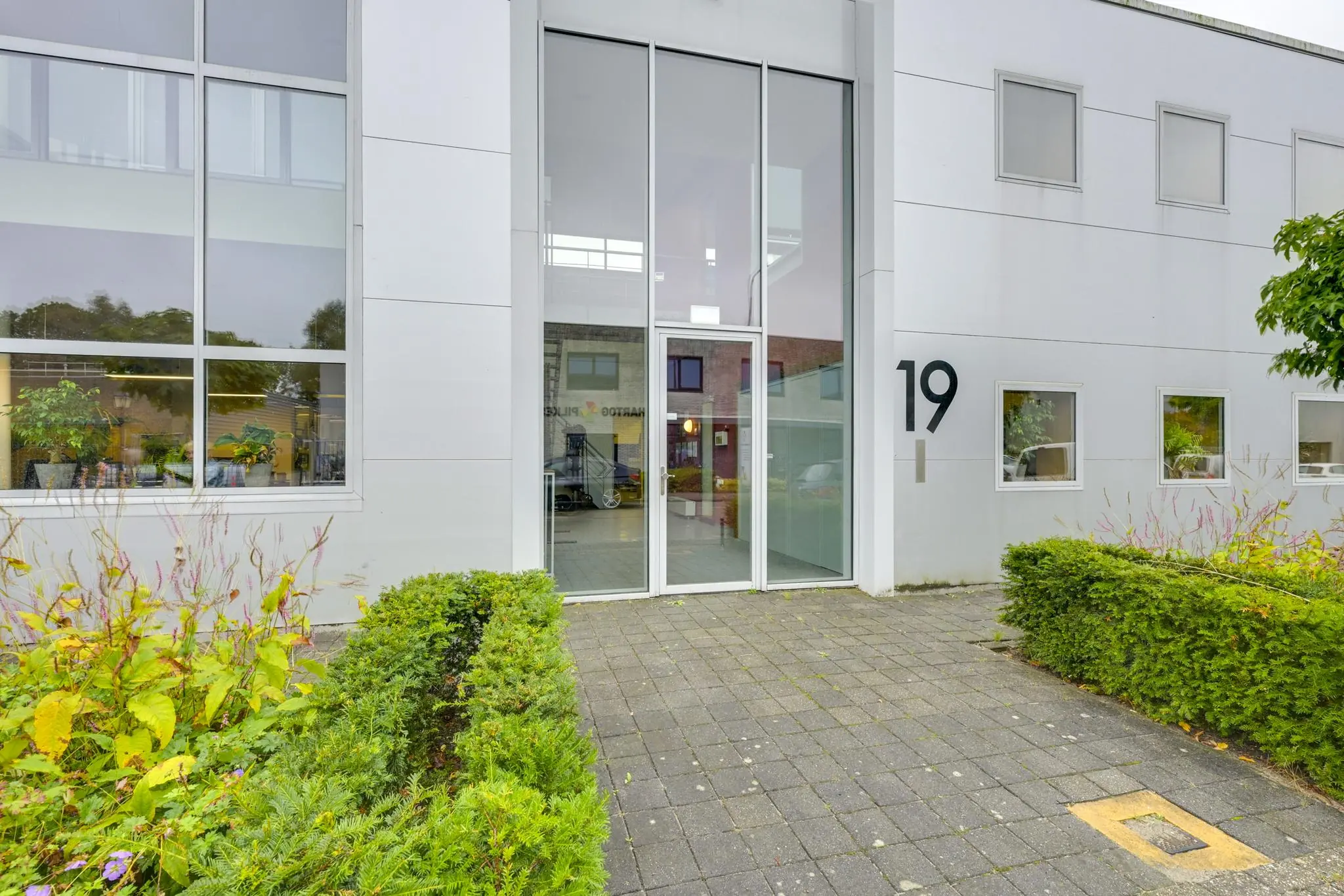 Vooraanzicht van een modern kantoorpand aan de Tennesseedreef 19 met glazen entree en goed onderhouden voortuin.
