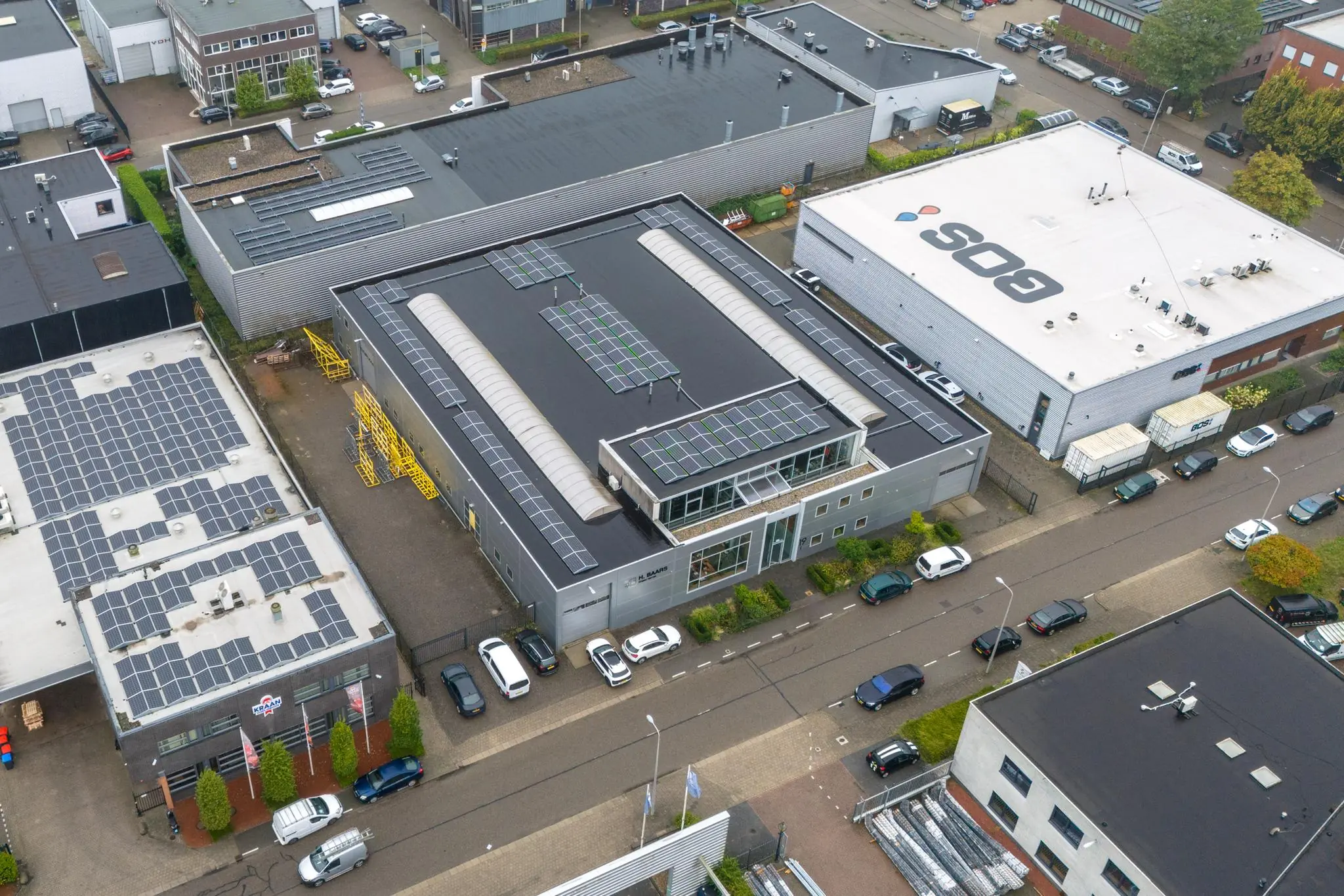 Luchtfoto van een bedrijventerrein aan de Tennesseedreef met meerdere bedrijfsgebouwen voorzien van zonnepanelen.