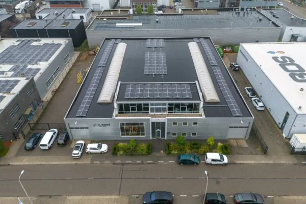 Luchtfoto van een bedrijfsgebouw aan de Tennesseedreef met zonnepanelen op het dak en geparkeerde auto's ervoor.