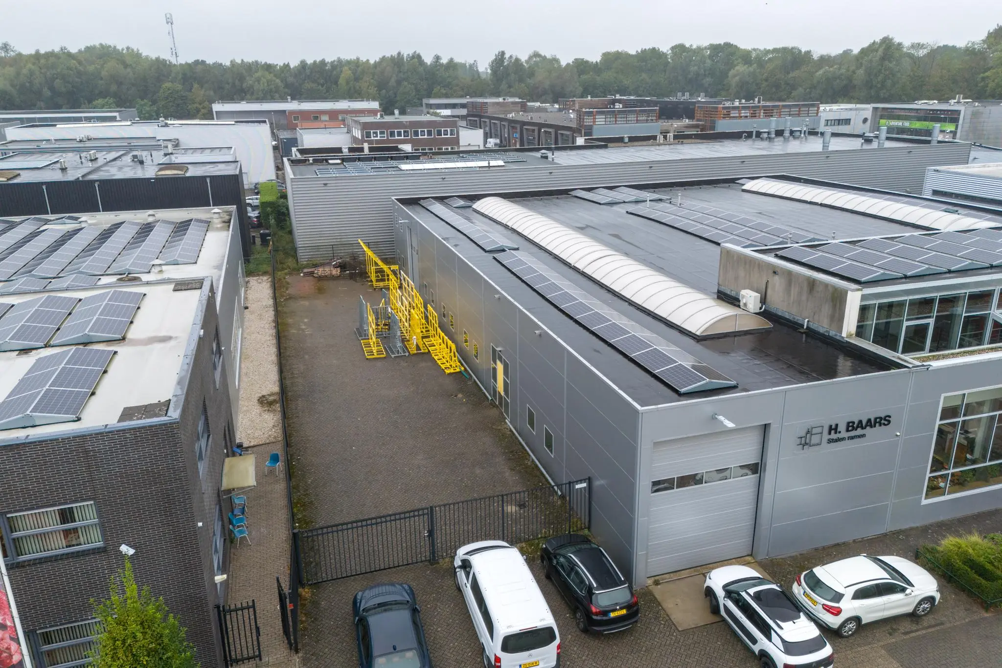 Luchtfoto van een bedrijfspand aan de Tennesseedreef met zonnepanelen op het dak en parkeerplaatsen ervoor.