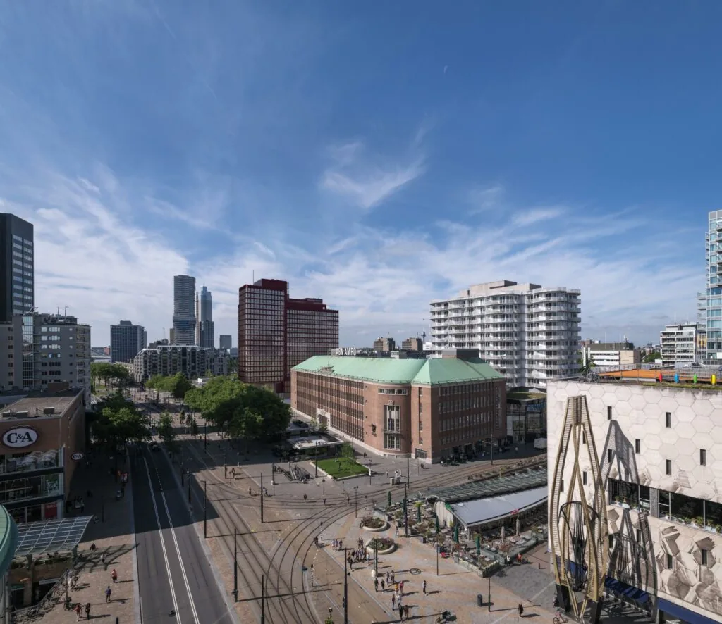 Luchtfoto van de Coolsingel in Rotterdam met het iconische postkantoor, moderne hoogbouw en druk stadsverkeer.