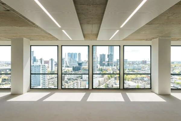 Licht en leeg kantoorpand met panoramisch uitzicht op de skyline van Rotterdam en de Erasmusbrug vanaf de Coolsingel.