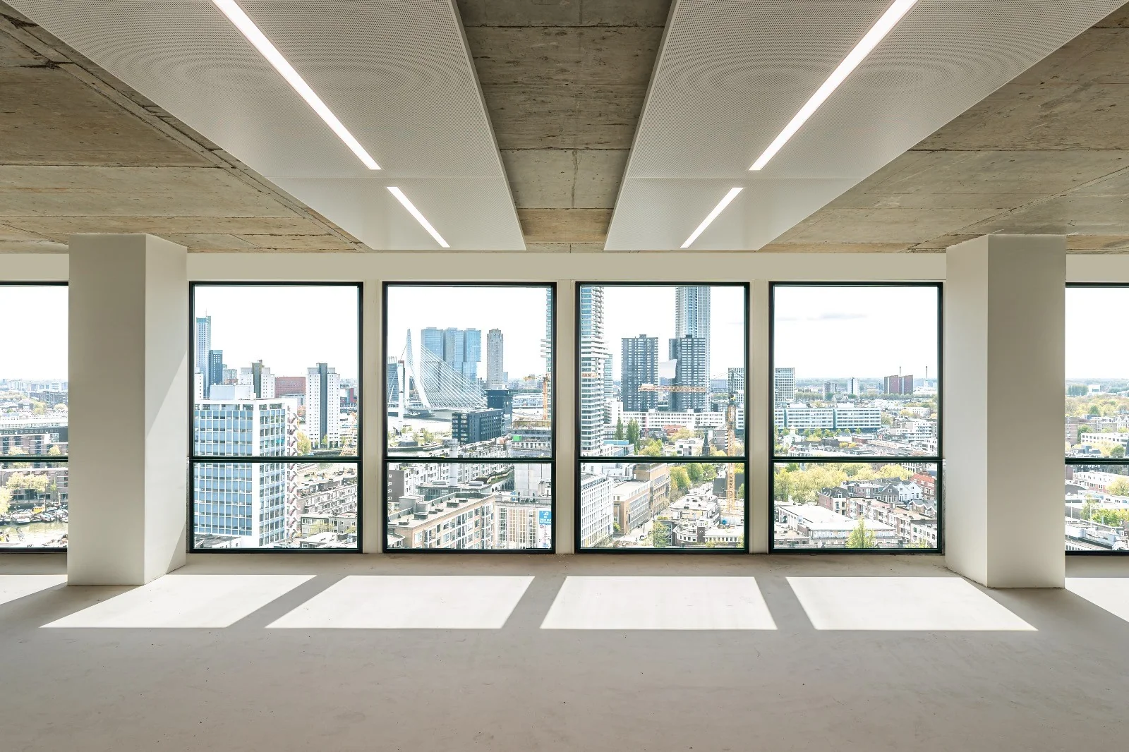 Licht en leeg kantoorpand met panoramisch uitzicht op de skyline van Rotterdam en de Erasmusbrug vanaf de Coolsingel.