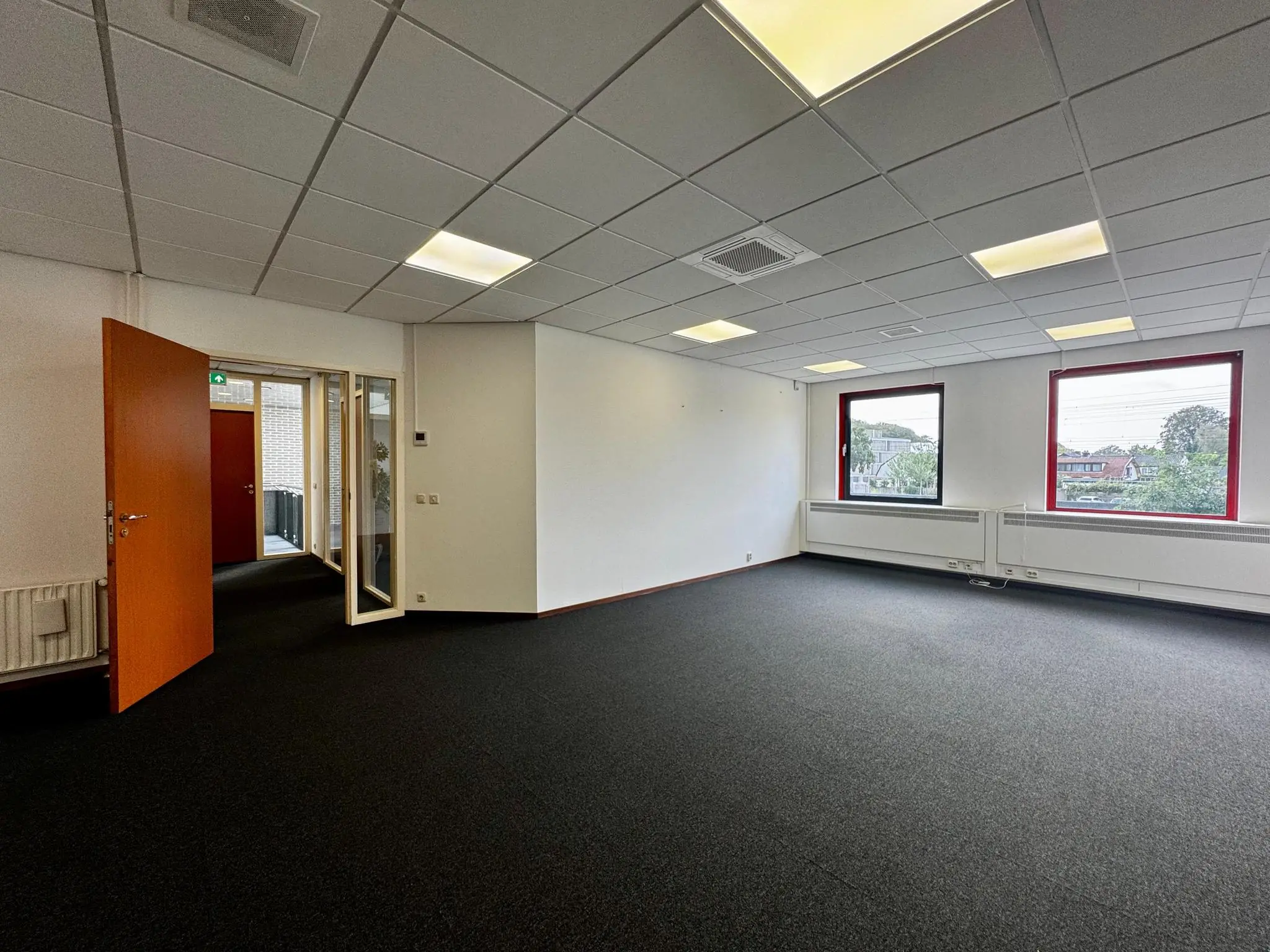 Licht en ruim kantoor met tapijtvloer, systeemplafond en grote ramen aan de Kwekerijweg.