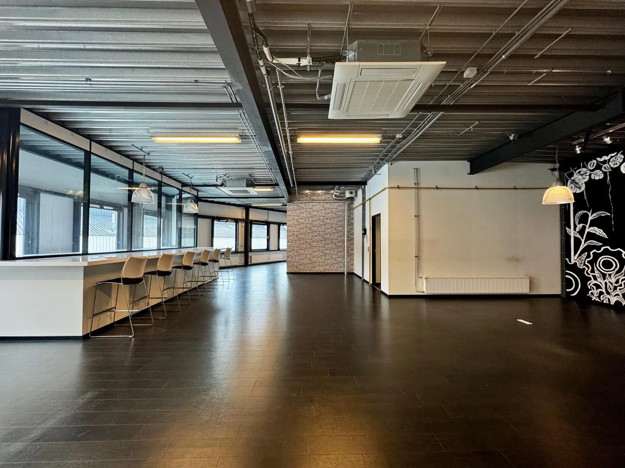 Ruime, moderne kantoorruimte aan de Kwekerijweg met hoge plafonds, barzitjes en grote ramen.