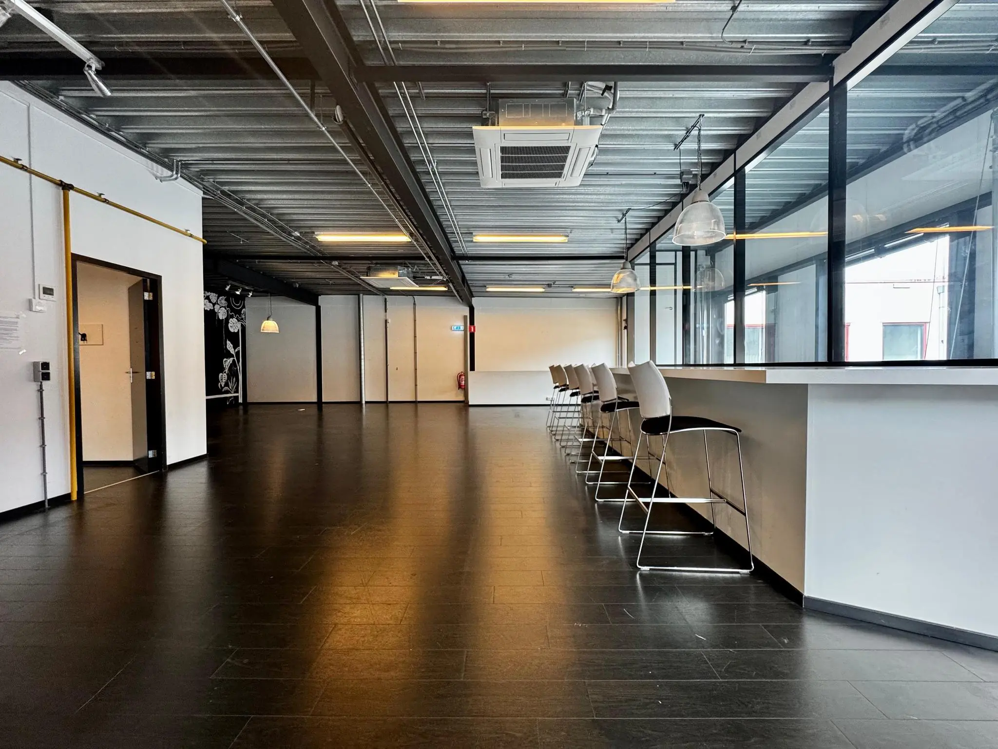 Moderne, industriële kantoorruimte aan de Kwekerijweg met hoge plafonds, bar met barkrukken en glazen wanden.