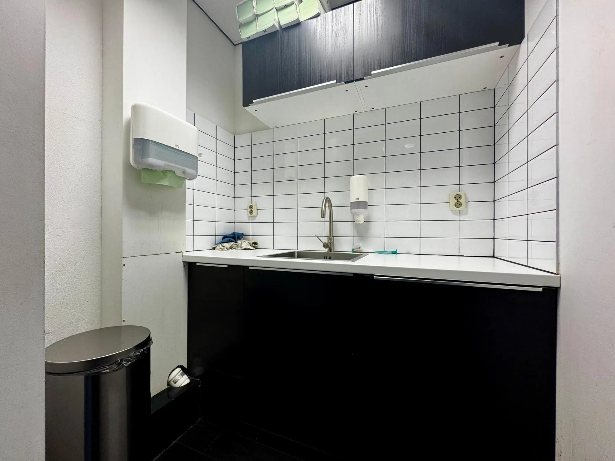 Kleine keuken met witte tegels, zwarte kasten en een roestvrijstalen wasbak aan de Kwekerijweg.