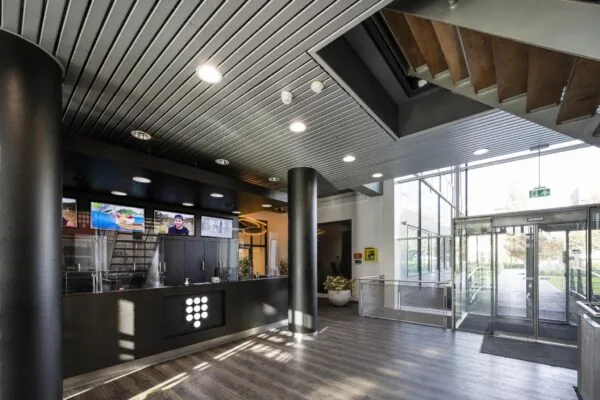 Moderne entreehal van gebouw Rietlandpark met receptiebalie, digitale schermen en glazen draaideur.