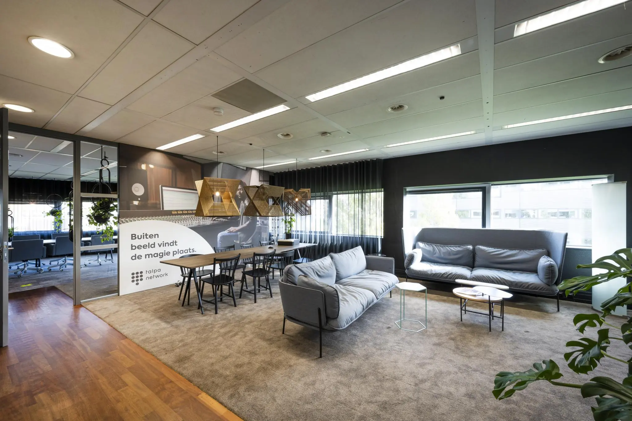 Moderne lounge- en vergaderruimte in het Rietlandpark-kantoor van Talpa Network met comfortabele zitplaatsen en stijlvolle verlichting.