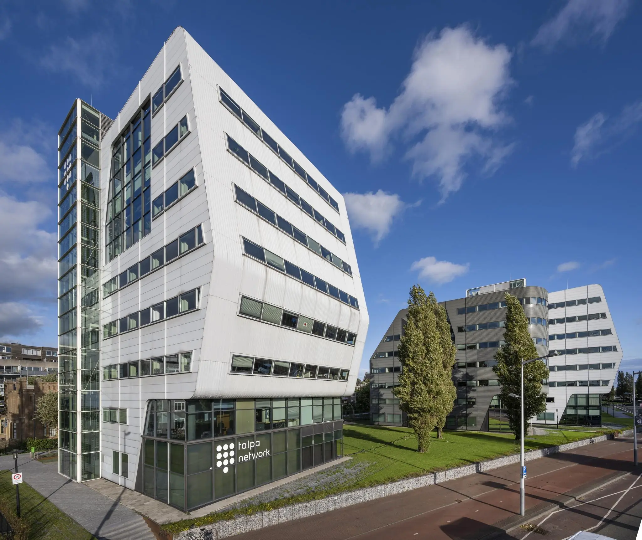 Modern kantoorgebouw van Talpa Network aan het Rietlandpark in Amsterdam onder een heldere blauwe lucht.