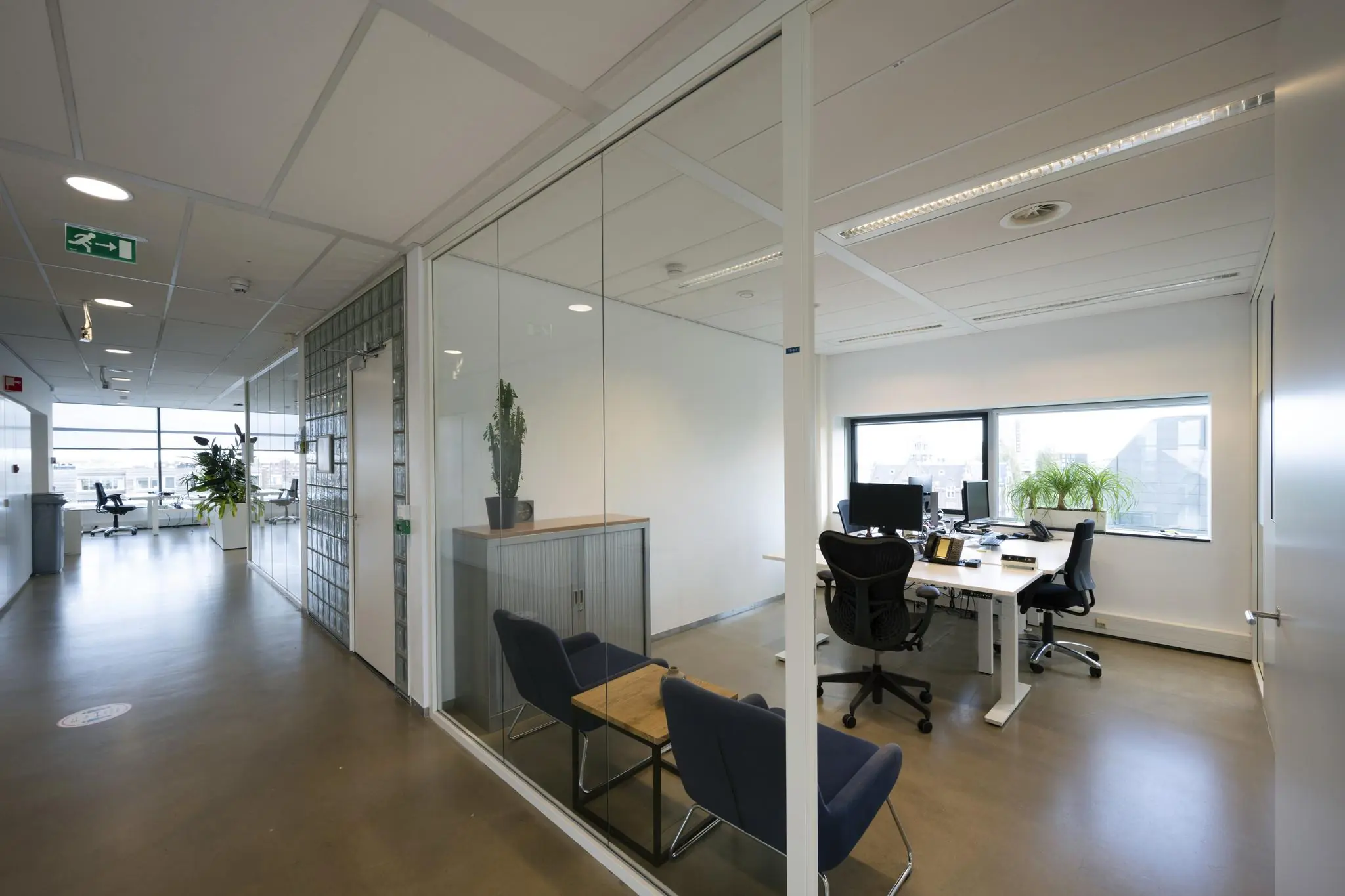 Modern kantoorinterieur in Rietlandpark met glazen wanden, bureaus, bureaustoelen en veel daglicht.