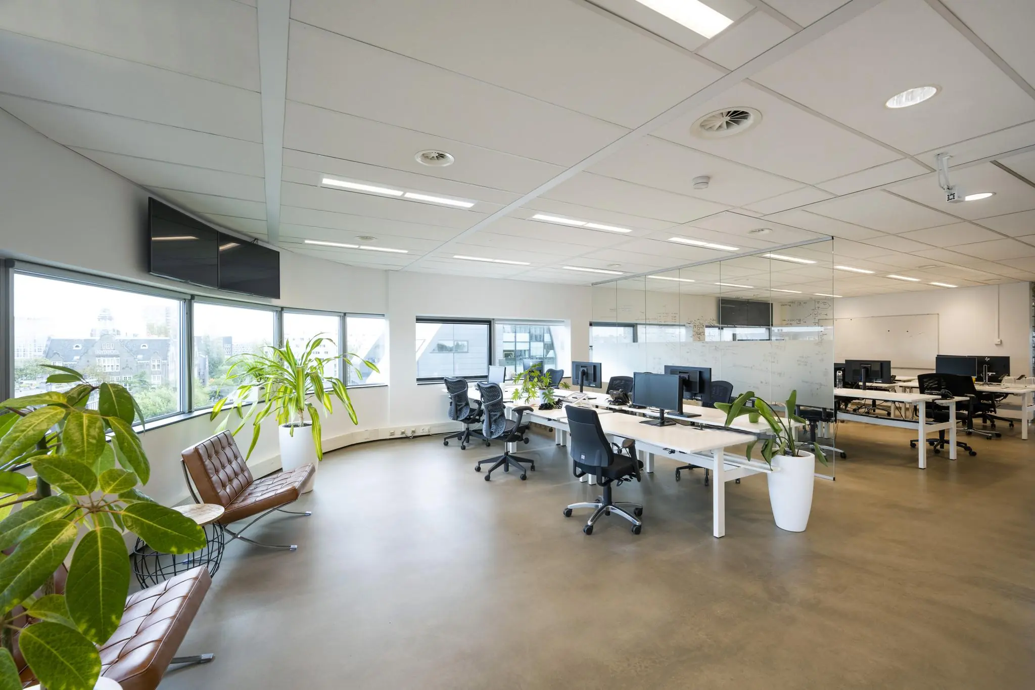 Moderne open kantoorruimte in Rietlandpark met werkplekken, planten en grote ramen.