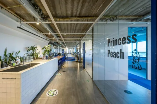 Moderne kantoorruimte aan de Johan Huizingalaan met een lange gang, open keuken en een vergaderruimte genaamd "Princess Peach".