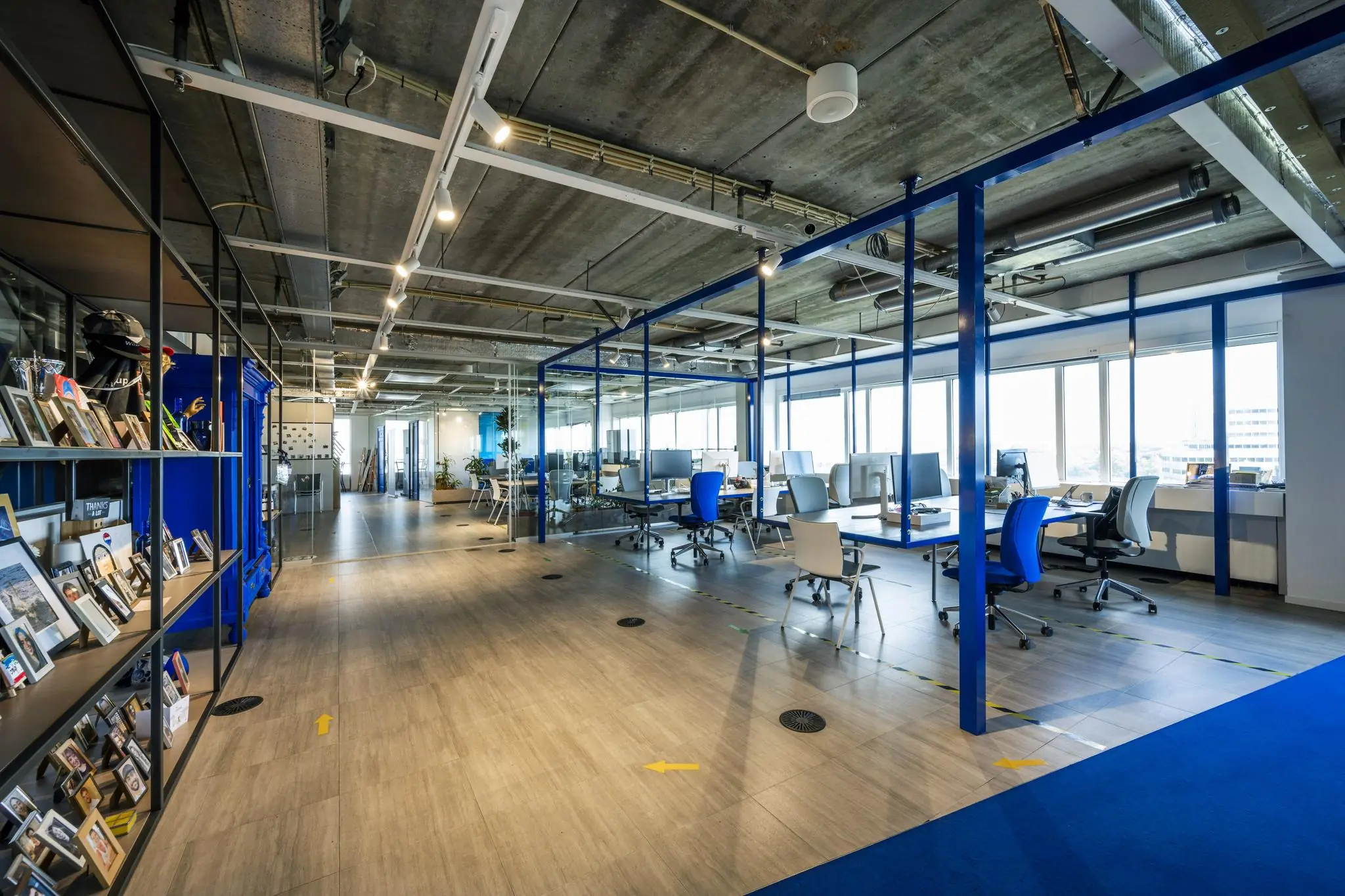 Een modern ingerichte kantoorruimte aan de Johan Huizingalaan met open werkplekken, blauwe accenten en industrieel plafond.