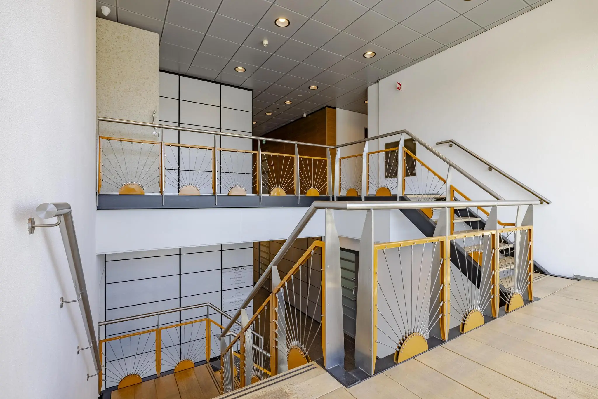 Moderne binnentrap met metalen leuningen en zonnestraalpatroon in een kantoorpand aan de Joan Muyskenweg.