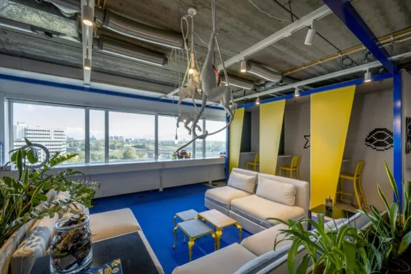 Moderne lounge- en werkruimte aan de Johan Huizingalaan met kleurrijk interieur, zithoeken en kunst aan het plafond.