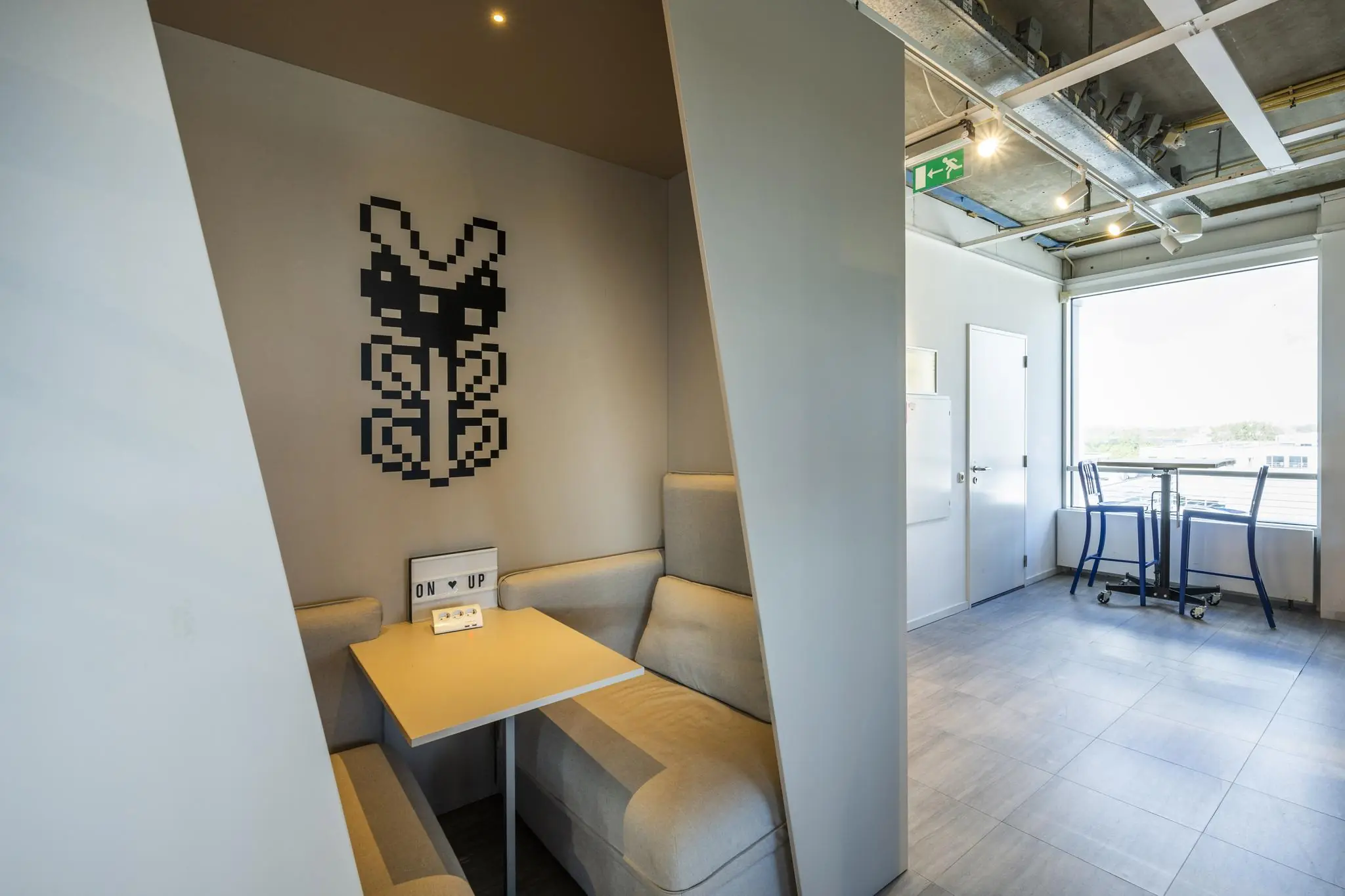 Moderne zithoek met een pixelkunst-decoratie aan de muur in een kantoorruimte aan de Johan Huizingalaan.