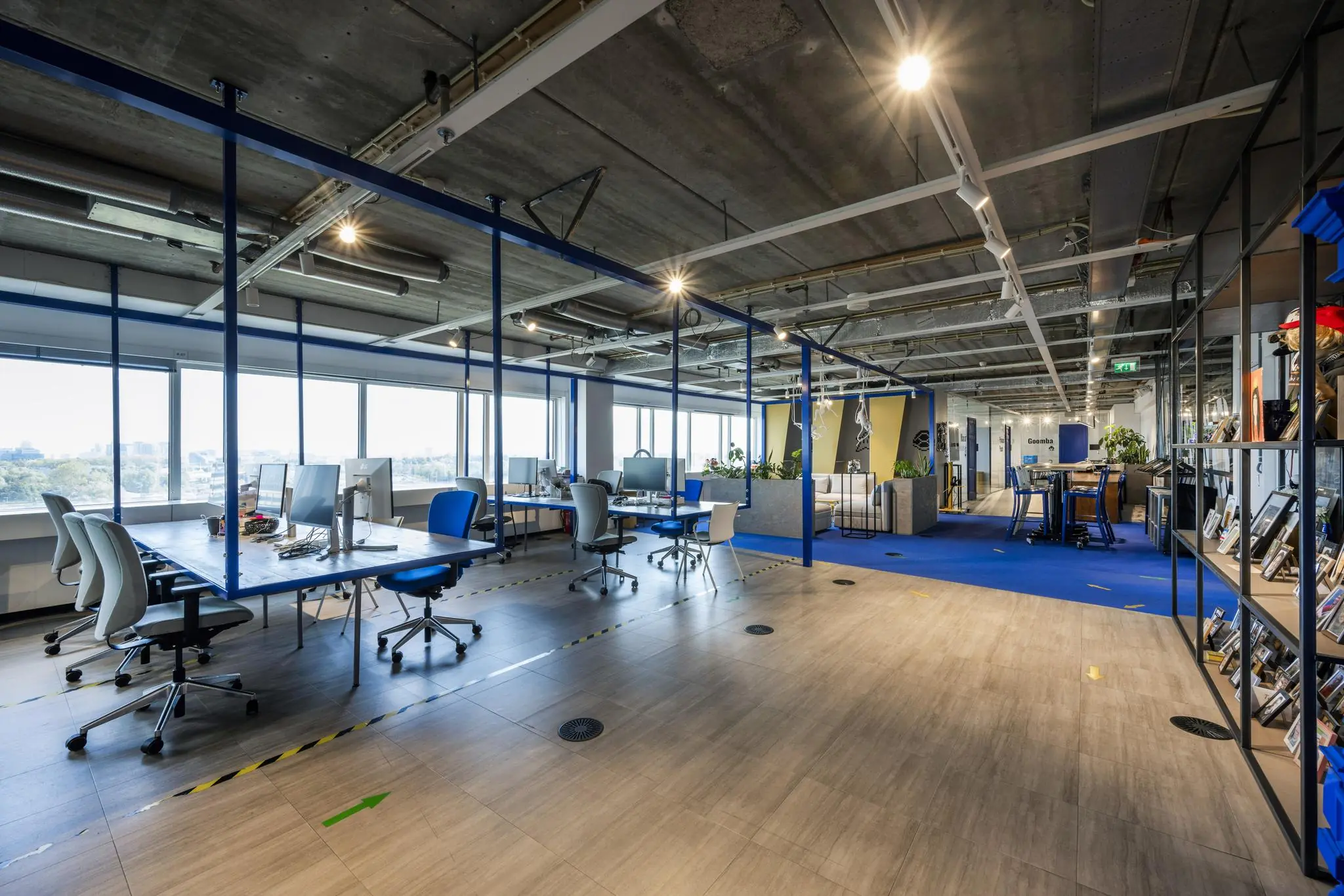 Modern kantoorinterieur aan de Johan Huizingalaan met open werkplekken, industriële plafondafwerking en blauwe accenten.