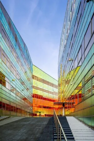 Kleurrijk modern kantoorgebouw aan de W. Dreesweg met reflecterende glasgevels en een trap naar de ingang.