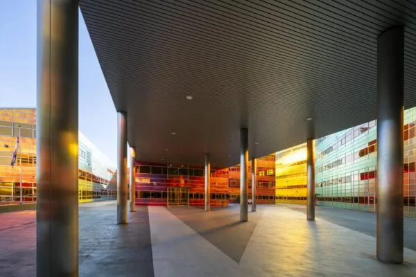 Moderne architectuur van een kleurrig gebouw aan de W. Dreesweg met hoge zuilen en reflecterende gevels in het zonlicht.