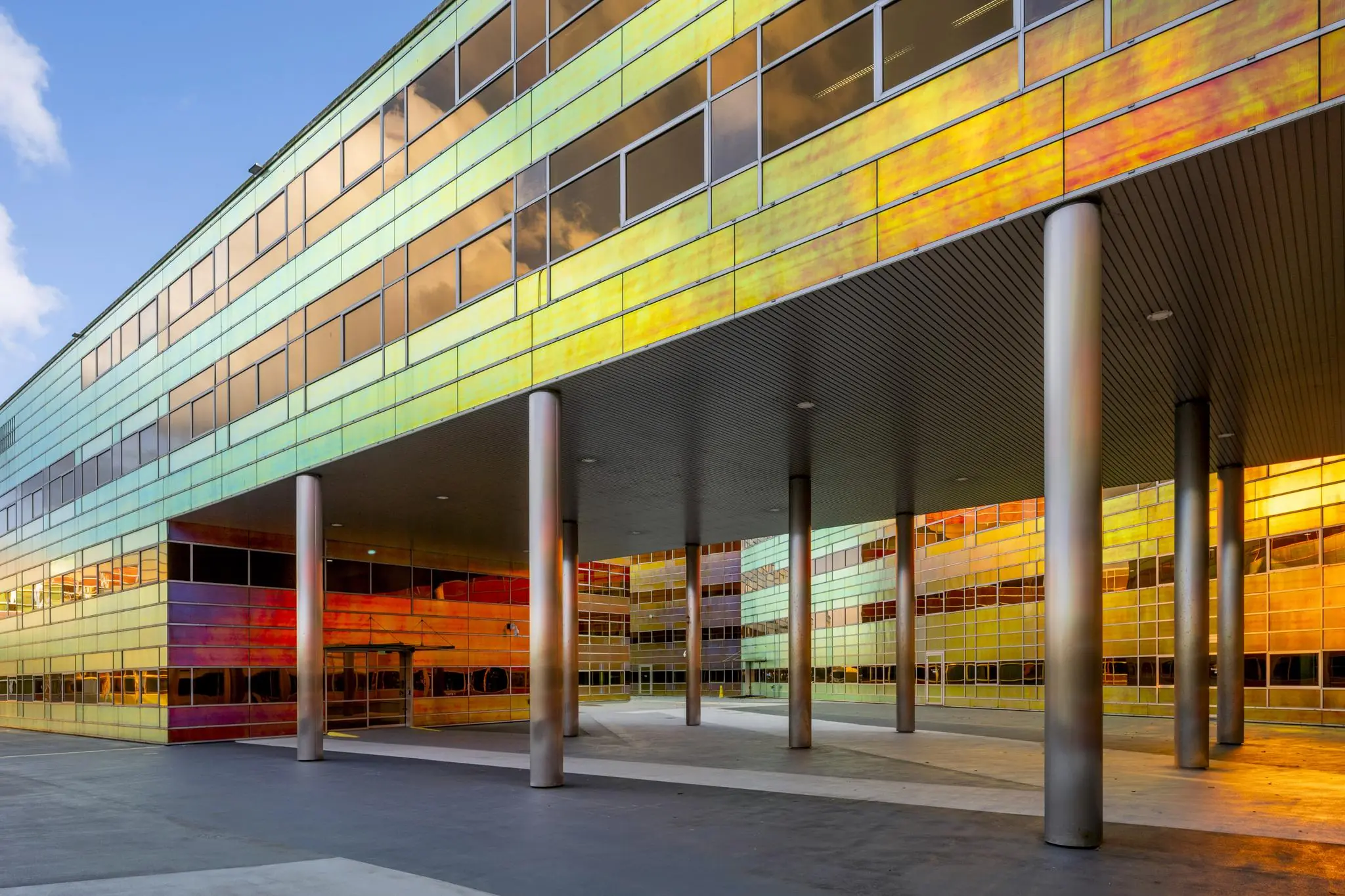 Modern gebouw aan de W. Dreesweg met opvallende iriserende gevelpanelen en metalen zuilen.