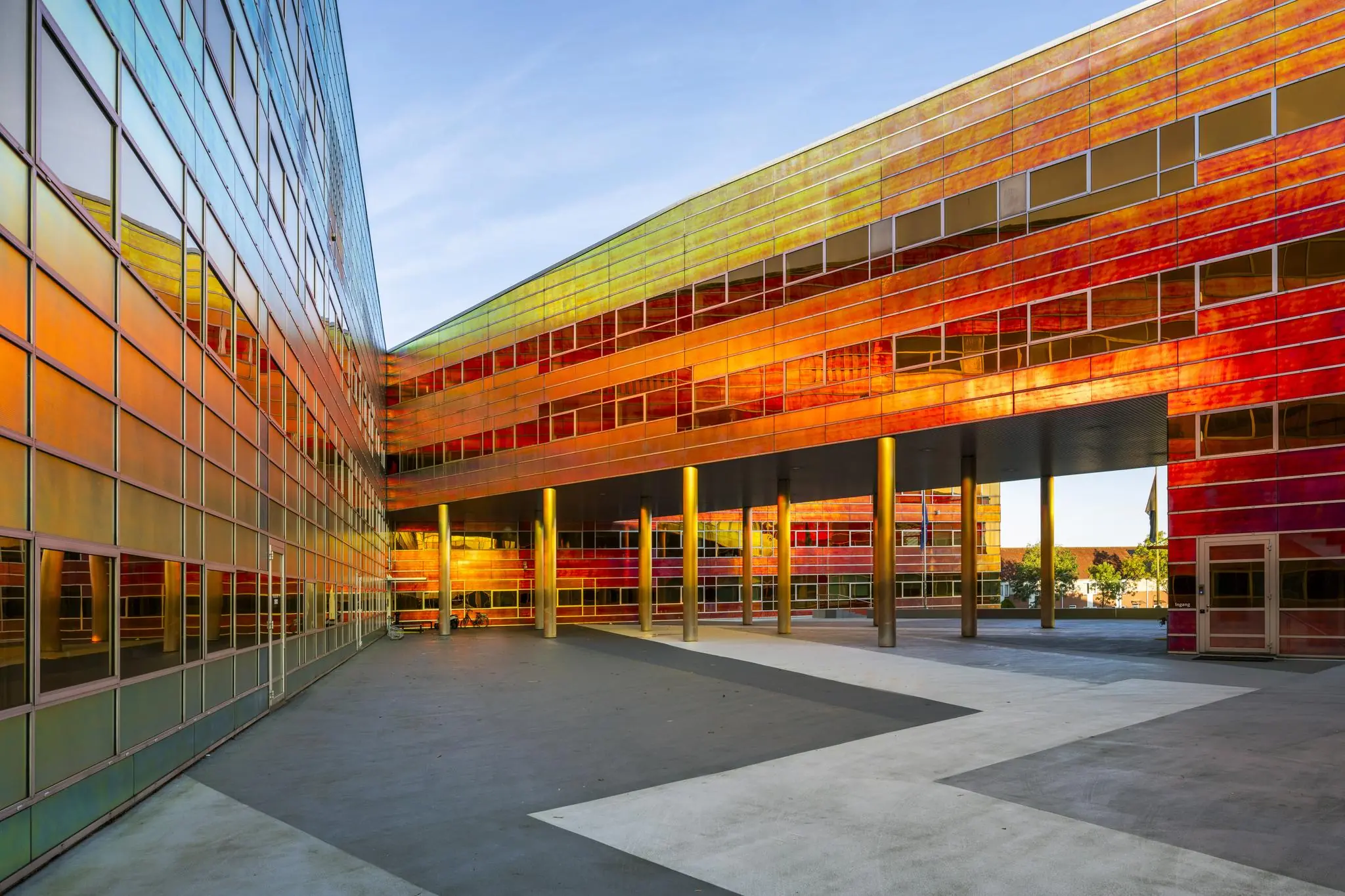Modern gebouw aan de W. Dreesweg met opvallende, reflecterende gevel in rood- en goudtinten.