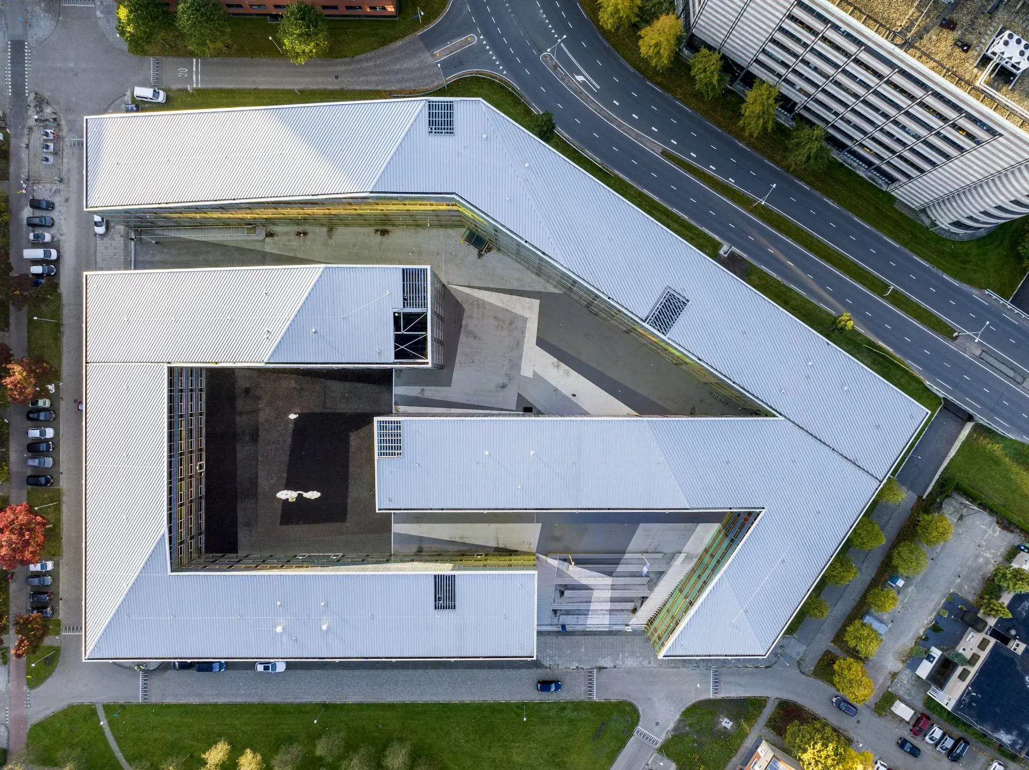 Luchtfoto van een modern, U-vormig gebouw aan de W. Dreesweg met omliggende wegen en parkeerplaatsen.
