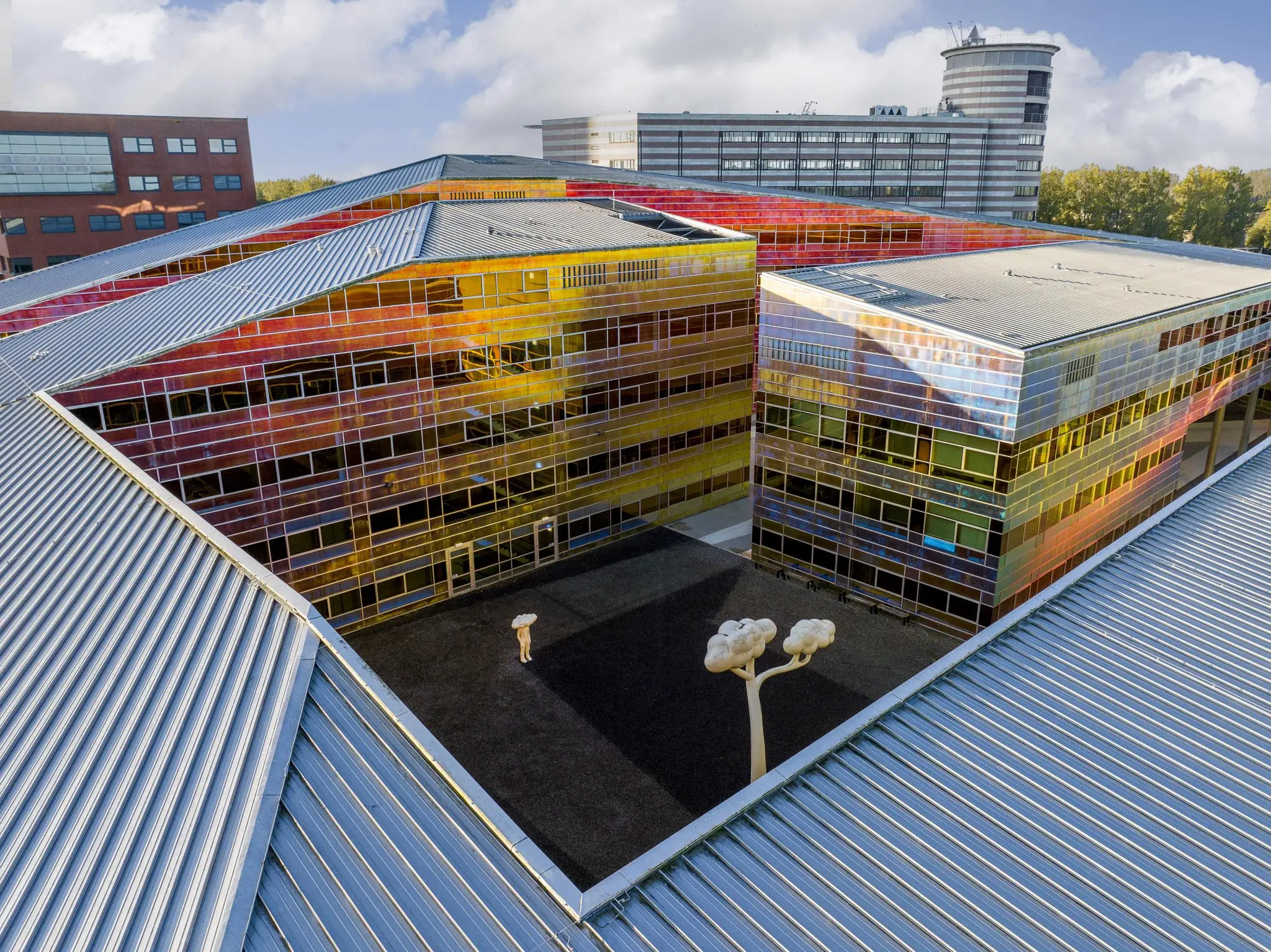 Luchtfoto van een kleurrijk gebouw aan de W. Dreesweg met een binnentuin en kunstobjecten.