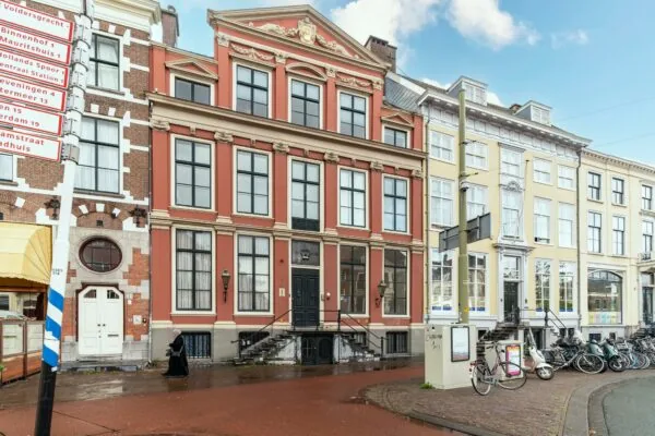Voorgevel van een klassiek herenhuis aan de Prinsestraat in Den Haag met rood-witte gevel en omliggende gebouwen.