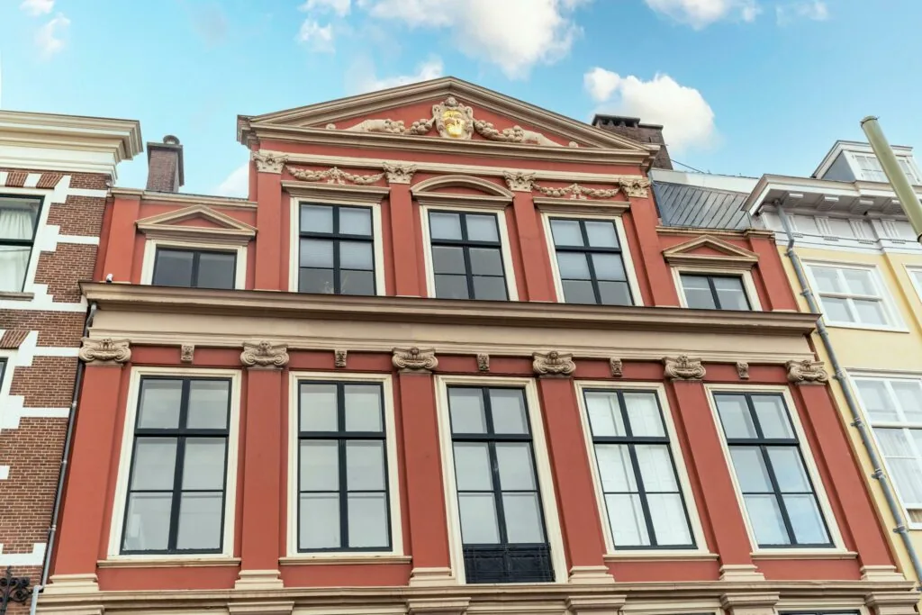 Een statig, rood herenhuis aan de Prinsegracht met klassieke gevelversieringen en grote ramen.