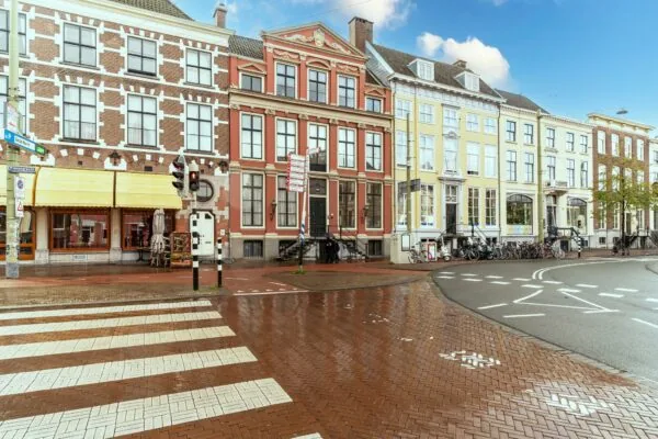 Rij historische herenhuizen aan de Prinsegracht in Den Haag op een natgeregende straat.