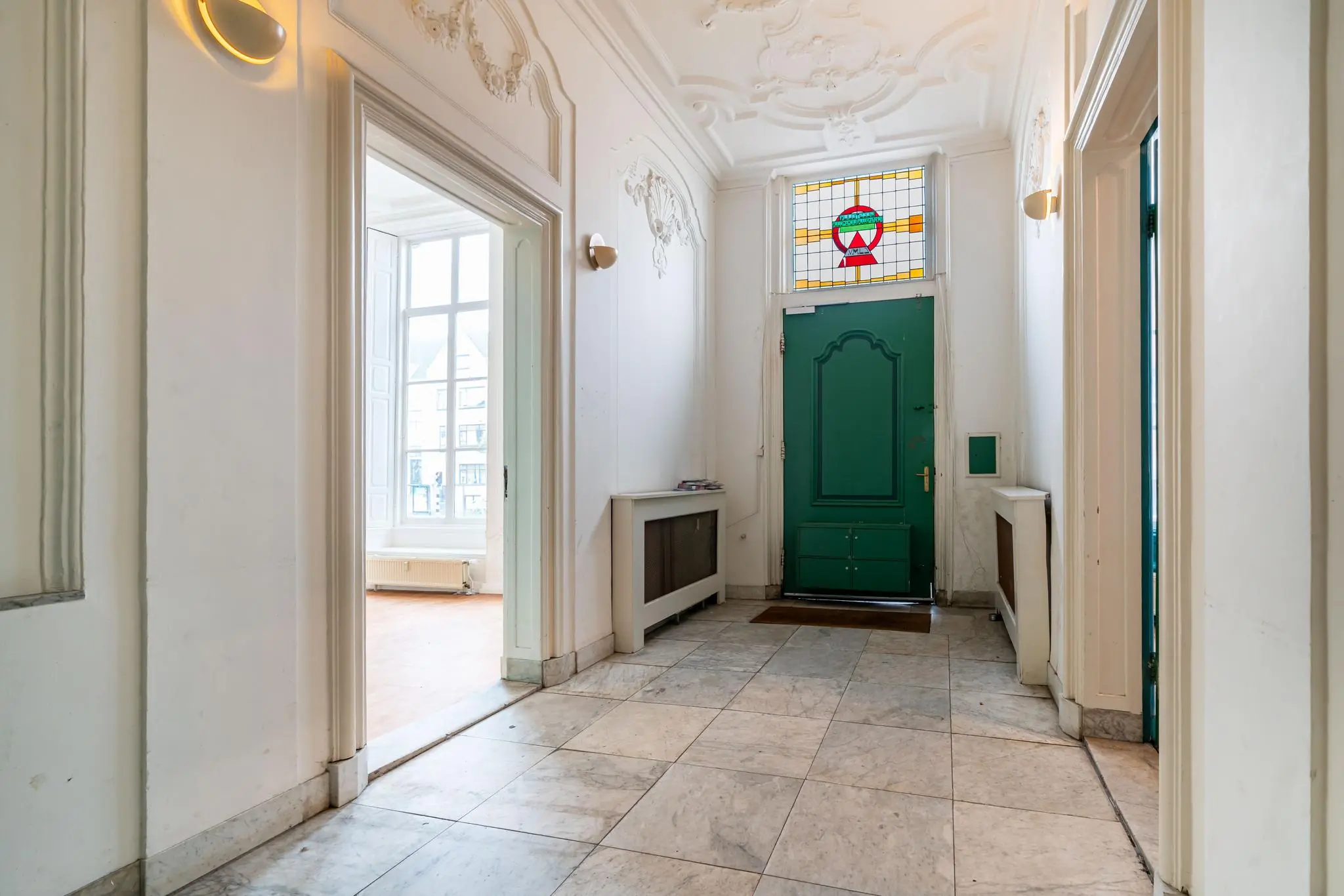 Entreehal van een klassiek pand aan de Prinsegracht met een groene deur en glas-in-loodraam.