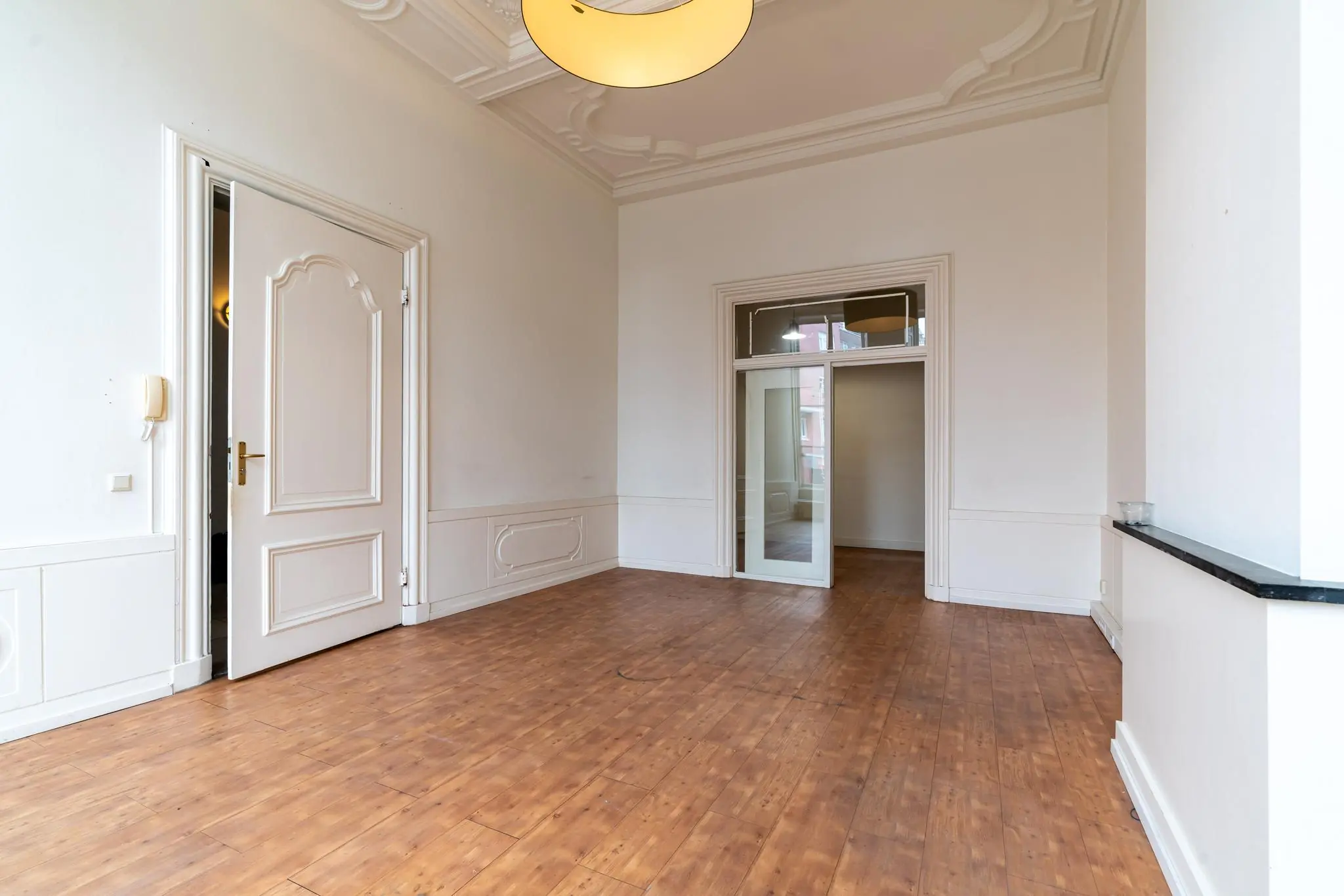 Lege kamer aan de Prinsegracht met houten vloer, hoge plafonds en klassieke witte wand- en deuropeningen.