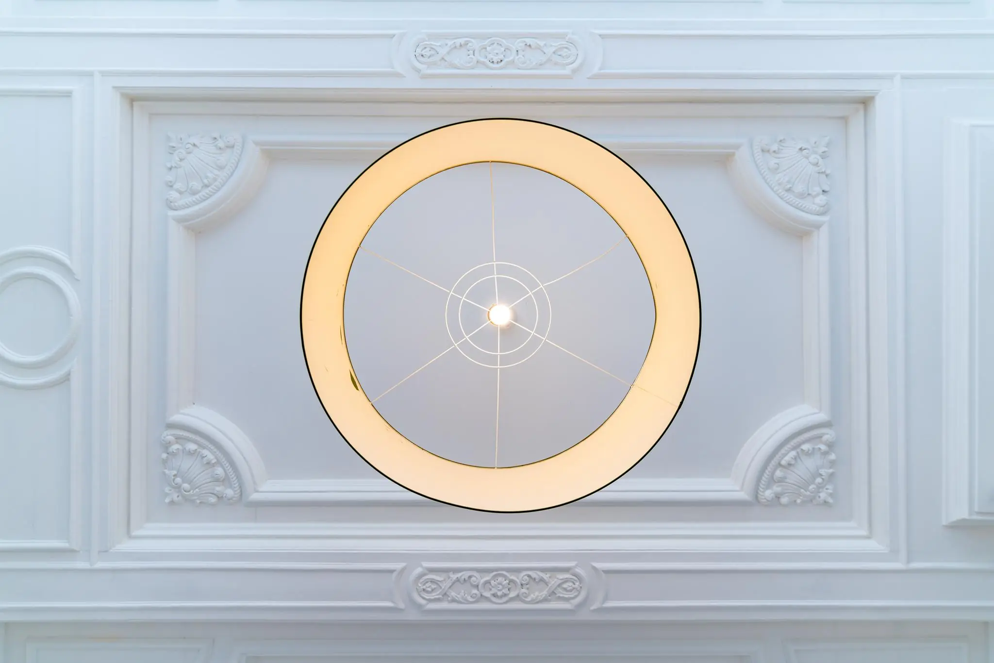 Moderne ronde plafondlamp aan een sierlijk wit plafond in een pand aan de Prinsegracht.