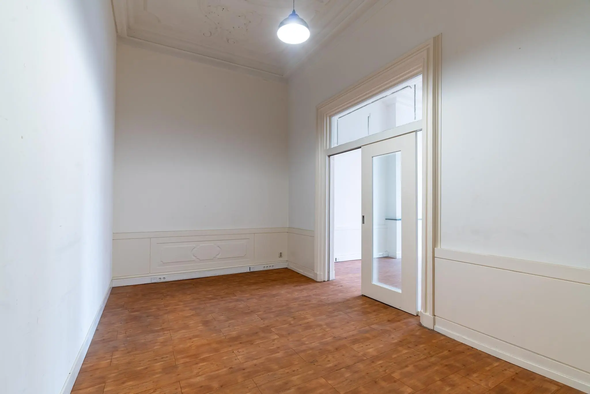 Lege kamer met houten vloer, hoge plafonds en witte schuifdeuren aan de Prinsegracht.