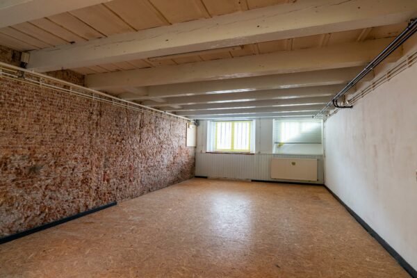 Lege souterrainruimte aan de Prinsegracht met houten plafond, bakstenen muur en twee ramen met tralies.