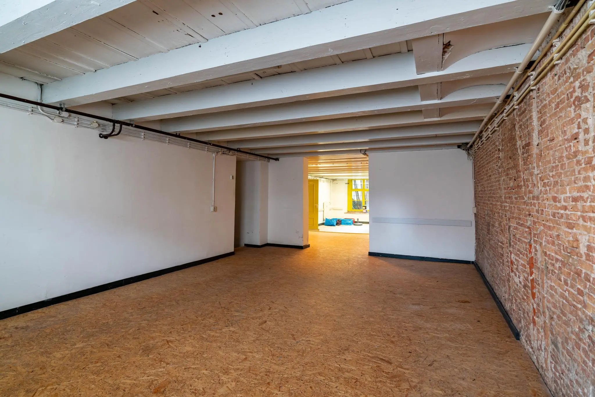 Leeg souterrain aan de Prinsegracht met zicht op een achtergelegen ruimte en houten balkenplafond.