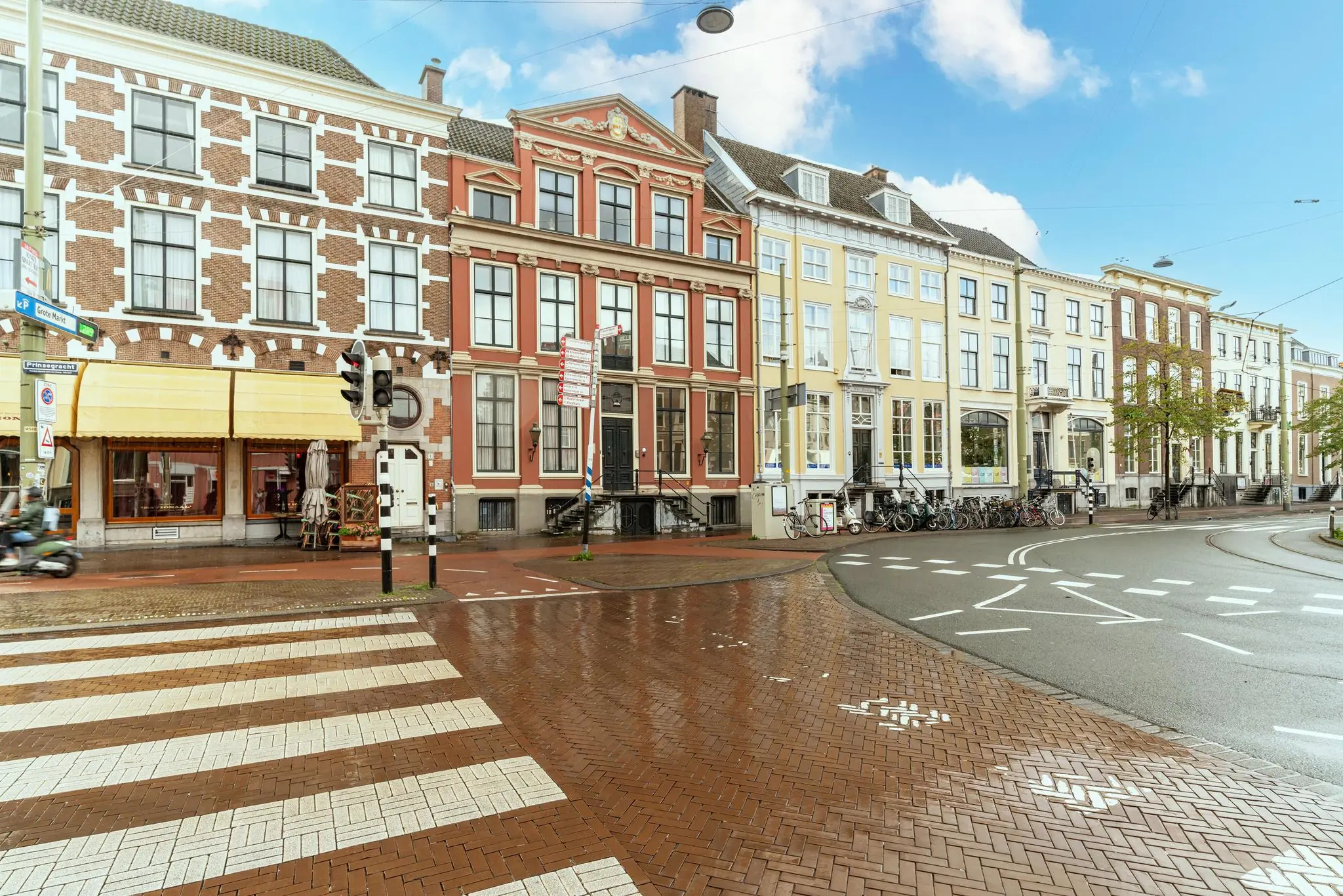 Straatbeeld van de Prinsegracht in Den Haag met historische panden, zebrapad en een nat wegdek na regen.