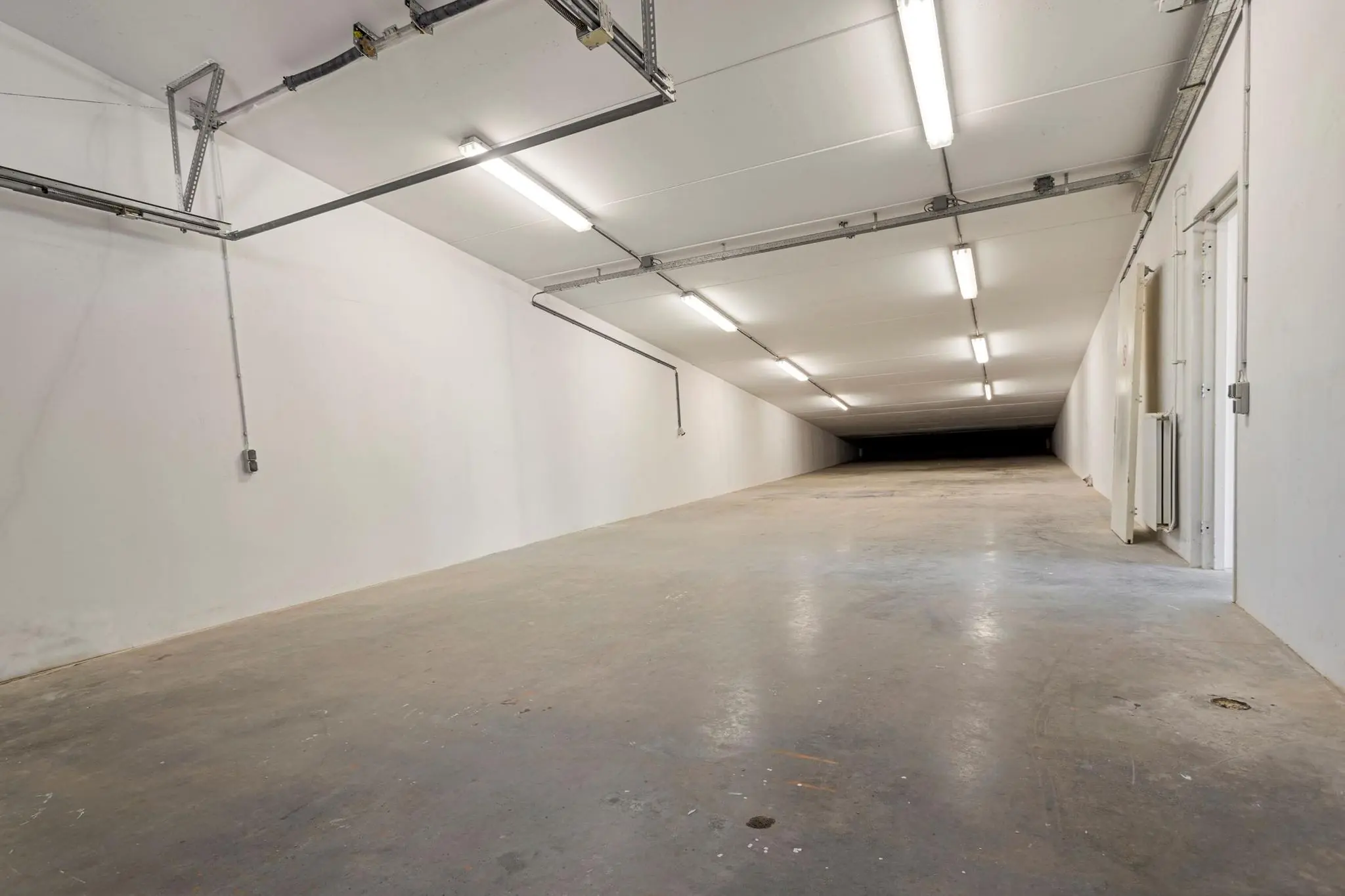 Lange, lege, wit verlichte parkeergarage of opslagruimte aan de Tijnmuiden.