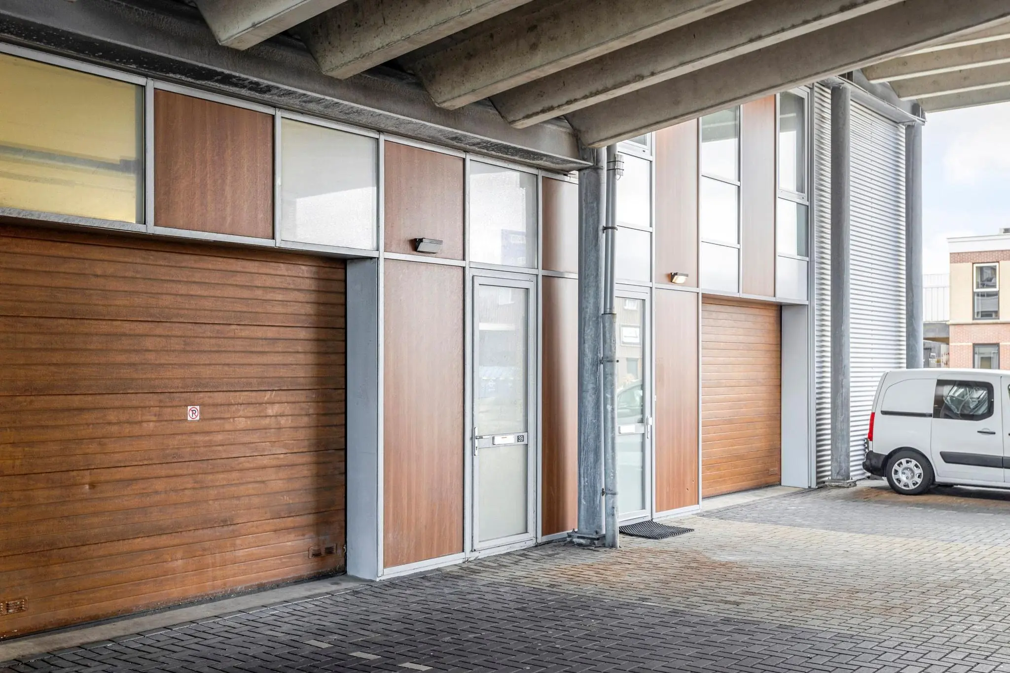 Bedrijfsunit aan de Tijnmuiden met houten gevelbekleding, roldeuren en een geparkeerde witte bestelbus.