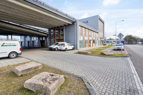 Bedrijventerrein aan de Tijnmuiden in Amsterdam met een kantoorgebouw onder een viaduct en geparkeerde auto's.