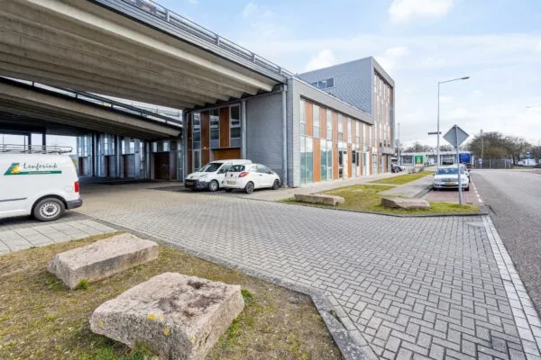 Bedrijventerrein aan de Tijnmuiden in Amsterdam met een kantoorgebouw onder een viaduct en geparkeerde auto's.