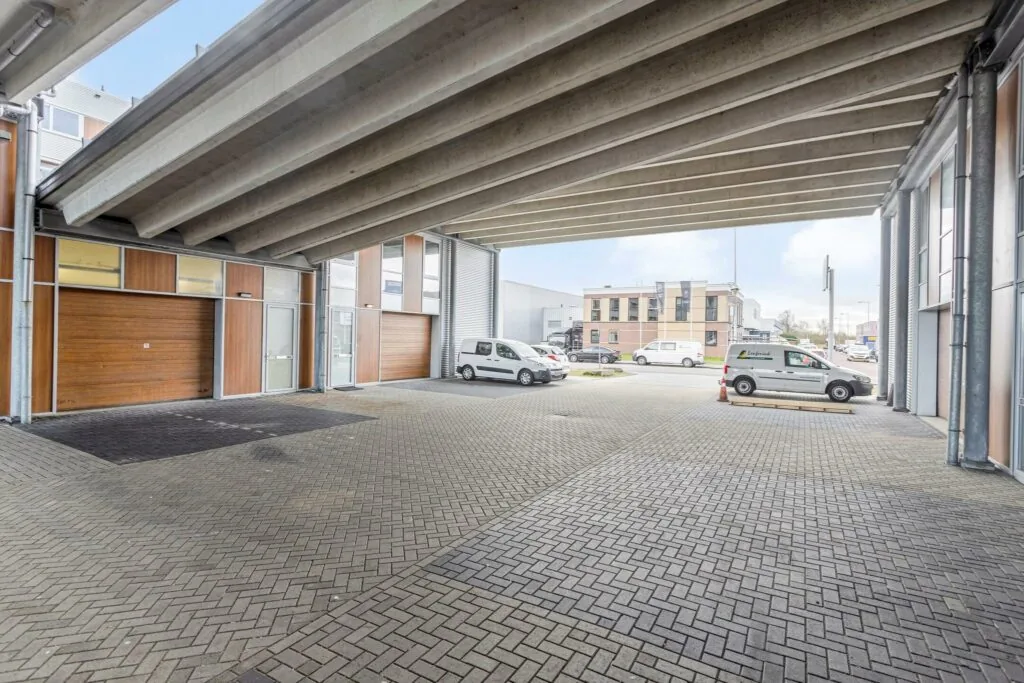 Overdekte parkeer- en bedrijfsruimte aan de Tijnmuiden met zicht op kantoren en geparkeerde bedrijfswagens.